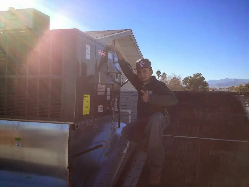 HVAC technician performing AC Tune-Up on a rooftop unit in Livonia