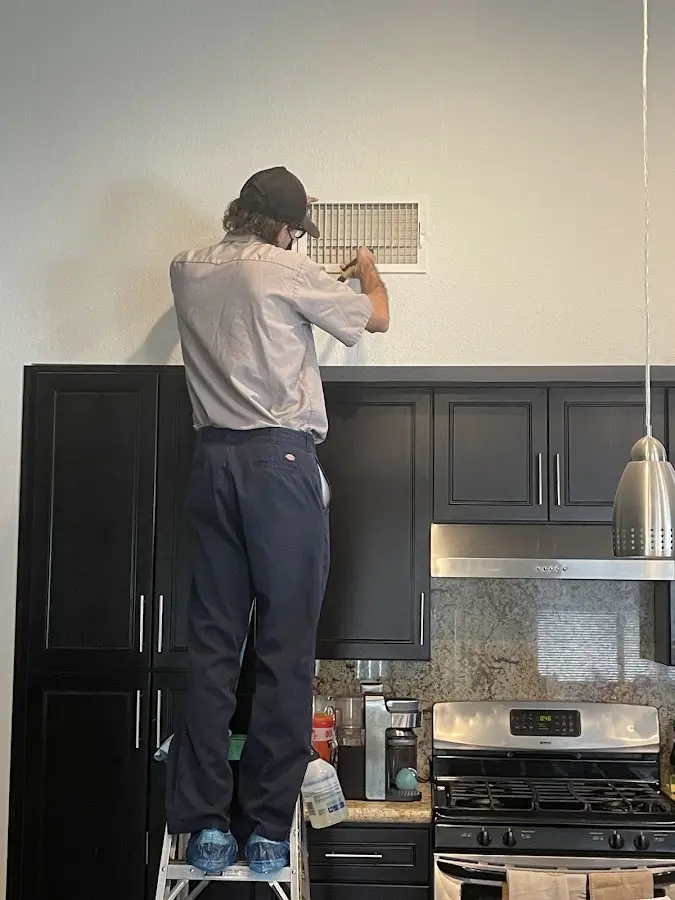 Technician inspecting an air vent during HVAC service in Livonia